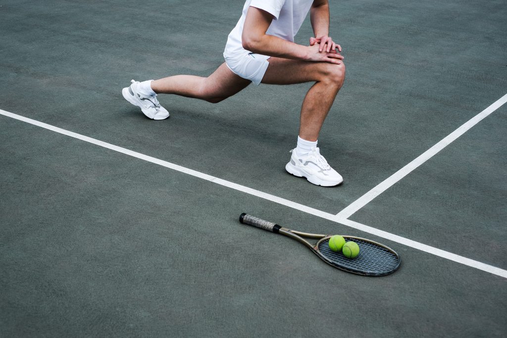Photo of a tennis player stretching his legs before a match